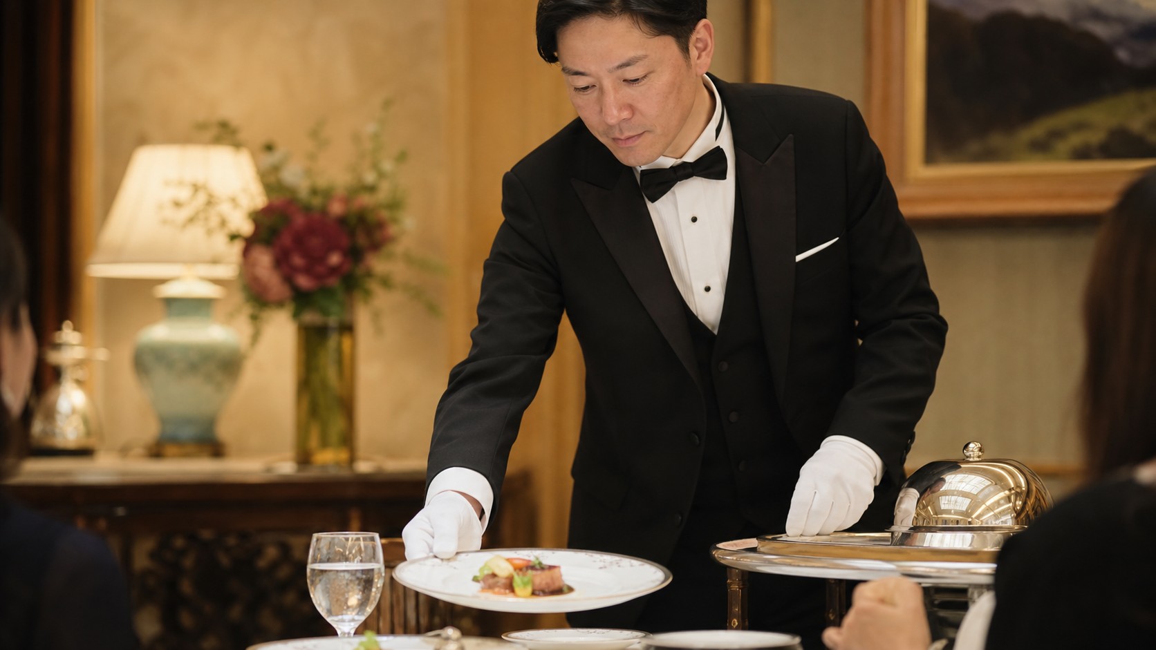 A Japanese butler presenting a plated course for attentive table-side Butler service
